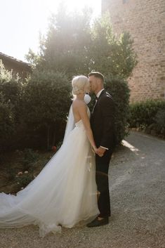 a bride and groom standing in front of some bushes