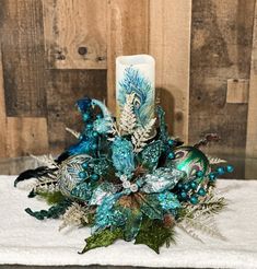 a blue candle is sitting on a white towel next to some green and silver decorations