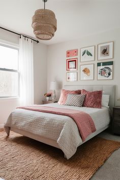 a bedroom with pink and white bedding, pictures on the wall and rugs