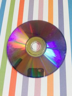 a cd that is sitting on top of a striped table cloth with a small hole in the middle