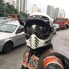 a man wearing a helmet and goggles standing in front of a line of parked cars