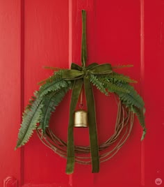 a green wreath hanging on a red door