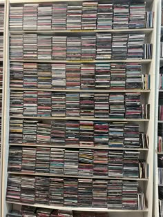 a large collection of cd's on shelves in a room full of dvds and cds