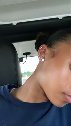 a woman with ear piercings in the back seat of a car