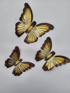 four gold butterflies sitting on top of a white surface