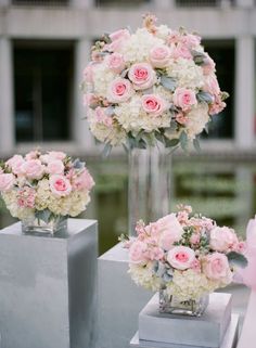 pink and white flowers in vases sitting on pedestals at an outdoor wedding ceremony