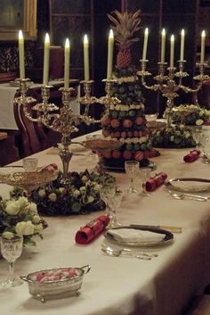 a table set with candles and flowers on it for a formal dinner or party in the dining room