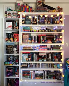 a book shelf filled with lots of books next to a wall covered in light bulbs