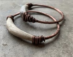 two bracelets with wooden beads on top of concrete floored area next to each other