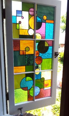 a glass window with different colors and shapes on the side of it in front of a door