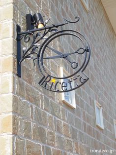 a clock mounted to the side of a brick building next to a street sign that says arceria