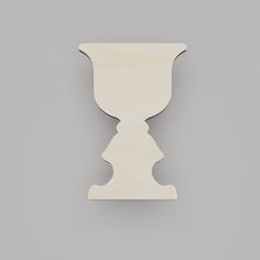 a white vase shaped object on a gray surface with the top half cut out to look like it is holding something