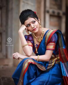 a woman sitting on the ground wearing a blue and red sari