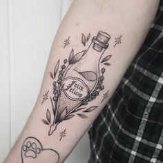 a person with a tattoo on their arm holding a bottle and paw prints in it