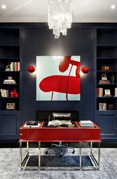 a red table sitting in front of a book shelf filled with books