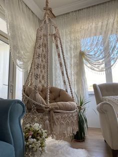 a living room with a hammock hanging from the ceiling next to two chairs