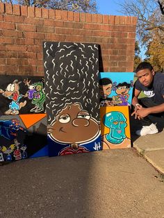 a man kneeling down next to some paintings