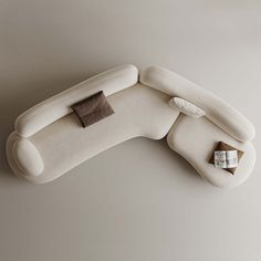 a white couch sitting on top of a floor next to a pillow and remote control