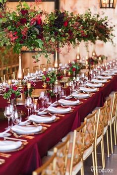 a long table is set up with red and gold place settings for an elegant dinner