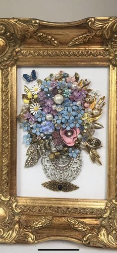 an ornate gold frame holds a bouquet of flowers in it, and is attached to the wall