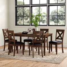 a dining room table with four chairs and a potted plant in the middle of it