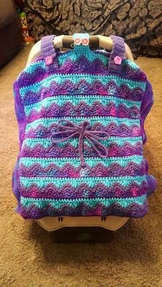 a purple and blue crocheted blanket sitting on top of a baby car seat