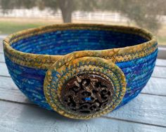 a blue and yellow bowl sitting on top of a wooden table next to a window