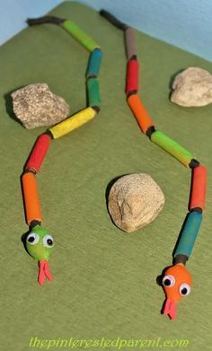 a snake made out of crayons and some rocks on a green tablecloth