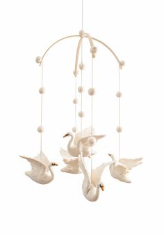 three white birds are hanging from a chandelier