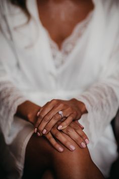 a close up of a person holding their hands together with the other hand on her lap