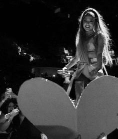 black and white photograph of a woman on stage with a heart shaped object in front of her