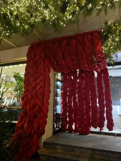 red fabric hanging from the ceiling in front of a window with christmas lights on it