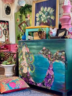 an old dresser is decorated with art and decorative items, such as vases and paintings