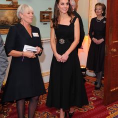 a woman in a black dress standing next to other people