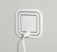 an electronic device is plugged in to the wall with a white cord that runs through it