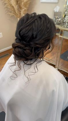 a woman sitting in a chair with her hair pulled back into a low bun style