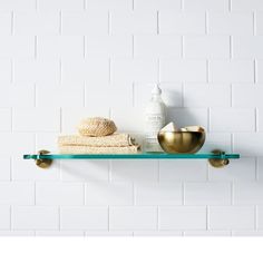 a shelf that has some towels and a bowl on it next to a white brick wall