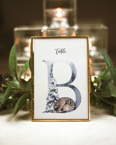 the table numbers are decorated with greenery and candles