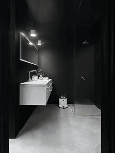 A bathroom with black walls, concrete flooring and a bright white vanity that stands out