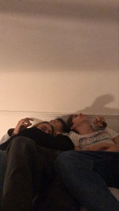 two people laying on a bed with their eyes closed