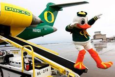 the mascot is standing next to an airplane