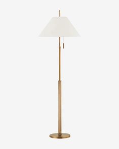 a brass floor lamp with a white shade