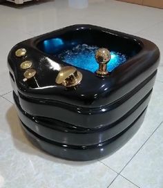 a large black box with gold knobs on the top and sides sitting on tile flooring