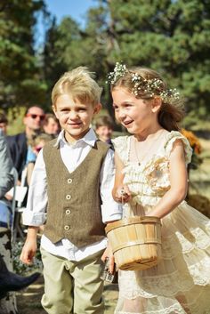 two young children are dressed up in formal clothing and holding buckets as they walk down the aisle