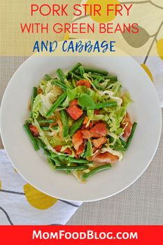 a white bowl filled with green beans and cabbage on top of a floral table cloth