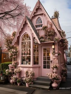 a pink house with flowers and potted plants