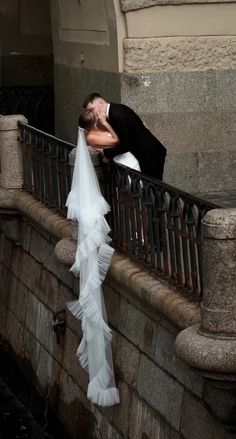 a bride and groom kissing on a balcony