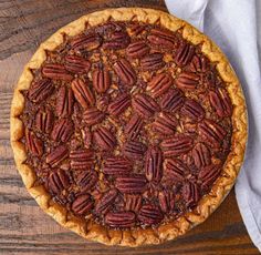 a pecan pie sitting on top of a wooden table next to a white napkin