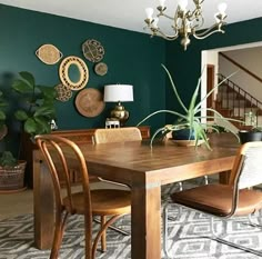 a dining room table with chairs and a plant in the center is surrounded by green walls