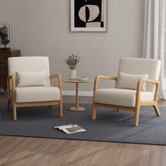 a living room with two chairs and a table in front of a painting on the wall